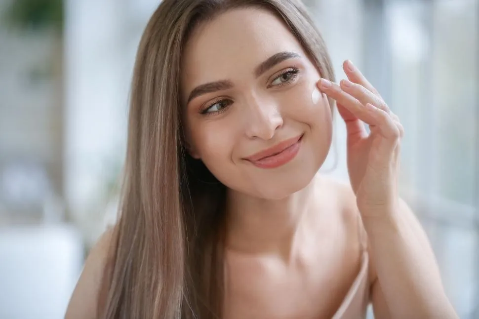a-woman-applying-cream-on-her-fa